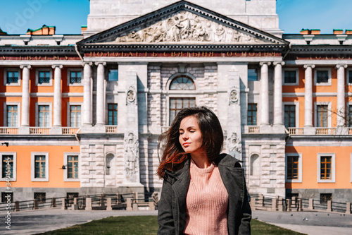 Portrait of a smiling girl in a coat on the background of an architectural monument, a historical castle in Saint Petersburg