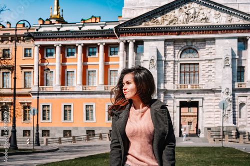 Portrait of a smiling girl in a coat on the background of an architectural monument, a historical castle in Saint Petersburg