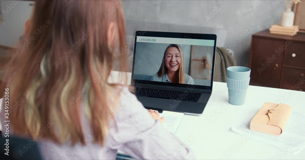 POV over shoulder, teen age girl talks to private female teacher leading remote lesson on laptop web conference call app POV over shoulder, teen age girl talks to private female teacher leading remote lesson on laptop web conference call app