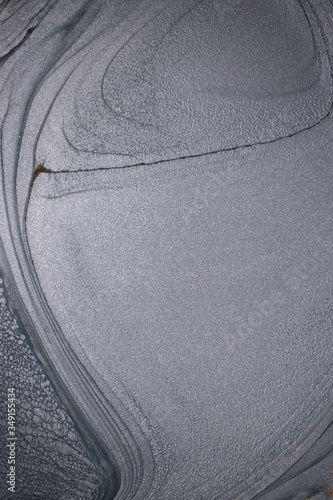 Macro photography of the dramatic black, monochrome abstraction, reminiscent of dragon scales or caked lava, shimmering with dark gray, silver and bronze accents. Alcoholic ink is mixed together.