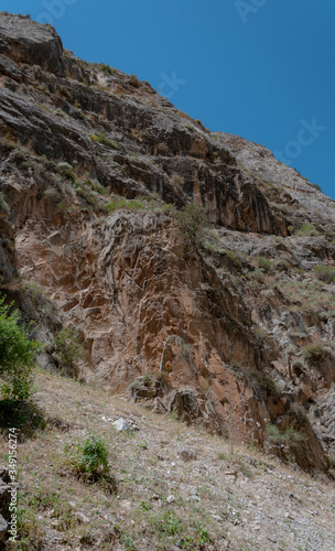 mountains of Central Asia. a narrow road between mountains. rapid river and sparse vegetation. there are no people.