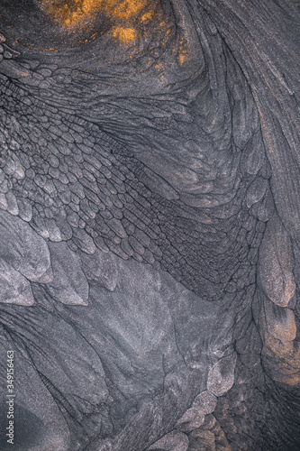 Macro photography of the dramatic black, monochrome abstraction, reminiscent of dragon scales or caked lava, shimmering with dark gray, silver and bronze accents. Alcoholic ink is mixed together.