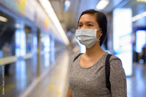 Face of young Asian woman with mask for protection from corona virus outbreak waiting at the subway train station