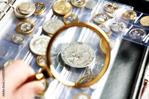 Old numismatics silver coins with magnifying glass