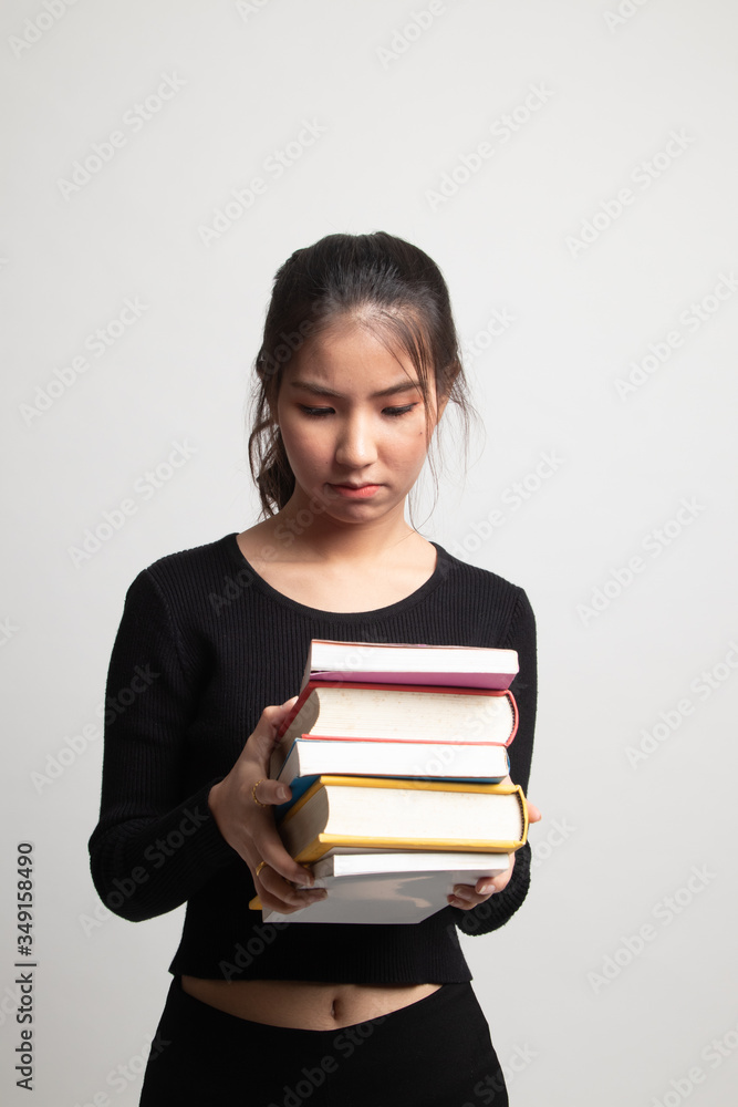 Unhappy young Asian woman studying with may books. Unhappy young Asian woman studying with may books.