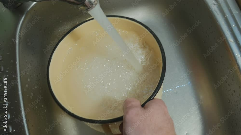 the cook carefully washes the rice in an enameled yellow pan. And drains the water. holding rice with the palm of your hand. He prepares the national dish Uzbek pilaf. 4K the cook carefully washes the rice in an enameled yellow pan. And drains the water. holding rice with the palm of your hand. He prepares the national dish Uzbek pilaf. 4K