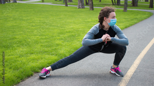 Sport during quarantine, coronavirus,covid-19.Young athletic woman in medical protective mask stretching legs after running jogging outdoor.Fitness girl doing lunges exercise,workout,training 