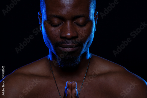 Hombre de raza negra sobre fondo negro meditando. Concepto de espiritualidad.