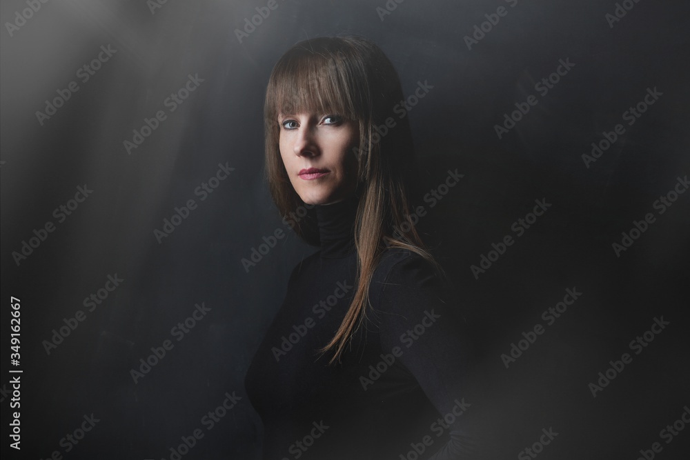 Beauty portrait of attractive young woman looking at camera, serious facial expression. Dark background. Beauty portrait of attractive young woman looking at camera, serious facial expression. Dark background.