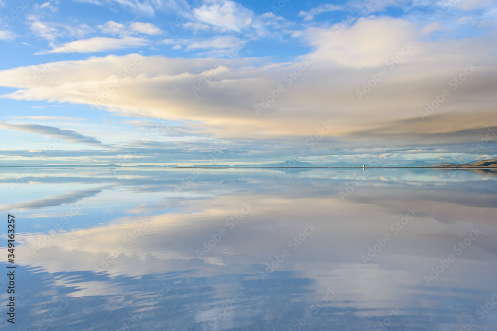 Misty  landscape with clouds and reflection in the lake , early morning, calm and quiet, pastel blue and golden color, Salar de Uyuni, Bolivia