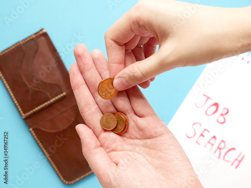 young women hold in hand dollar and euro coins coins, notebook with job search phrase, brown wallet on blue background. looking for a work, last money, poverty, unemployment, job loss concept photo