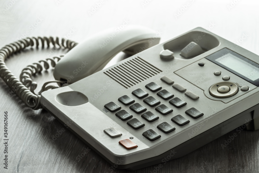 Desk phone on the desk with the handset off. Selective focus. Desk phone on the desk with the handset off. Selective focus.