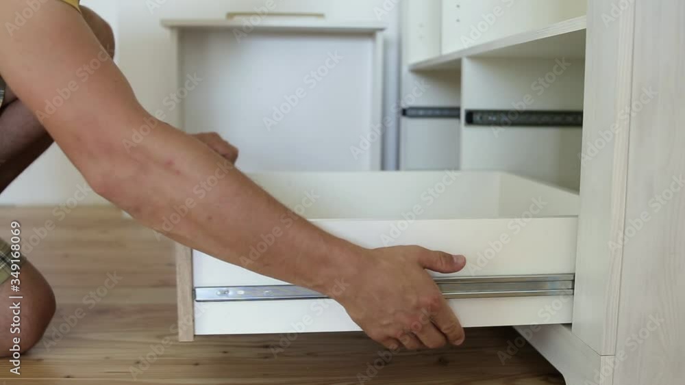 Close up of male carpenter hands assembling furniture cupboard and installing wooden new drawer. Close up of male carpenter hands assembling furniture cupboard and installing wooden new drawer.
