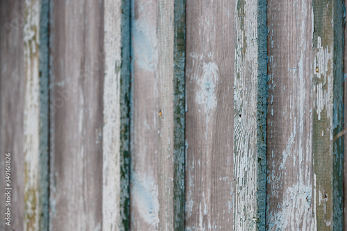 Part of an old fence of painted wooden boards on the street. Old wooden fence made of flat boards. Faded texture with turquoise paint. Copy space. Selective focus