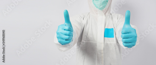 male model in PPE suite and face mask doing two thumbs up hand sign on white background.