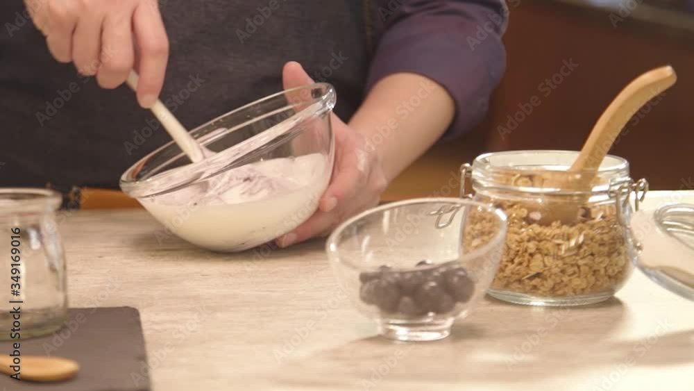 Hand mixing the yogurt inside glass bowl - slide right Hand mixing the yogurt inside glass bowl - slide right