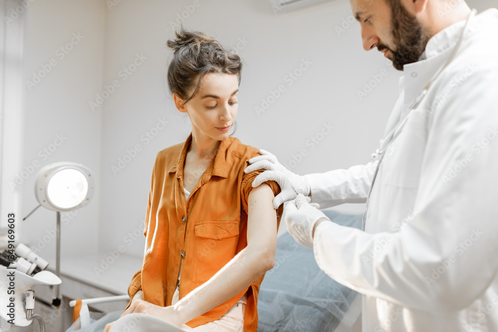 Obraz premium Healthcare worker gives an injection of a vaccine or some medication to a young girl in the office. Vaccination concept