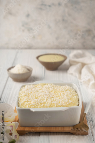 coconut cake in a ceramic bowl on a white wooden table, copy space