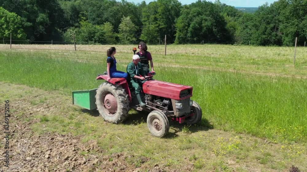 Farmer with apprentice riding tractor in farmland Farmer with apprentice riding tractor in farmland