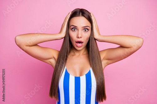 Photo of pretty shocked lady long straight hairstyle smooth bronze body skin not believe eyes epic fail arms on head wear white blue striped bodysuit isolated pastel pink color background