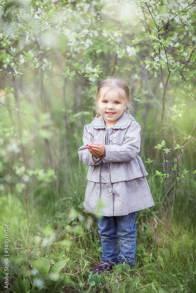 Girl walks in the garden, spring, may, cherry blossoms, spring blooming, happy child Girl walks in the garden, spring, may, cherry blossoms, spring blooming, happy child