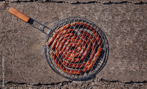 Grilling basket with roasted Bavarian  sausages on concrete background. BBQ outside.
