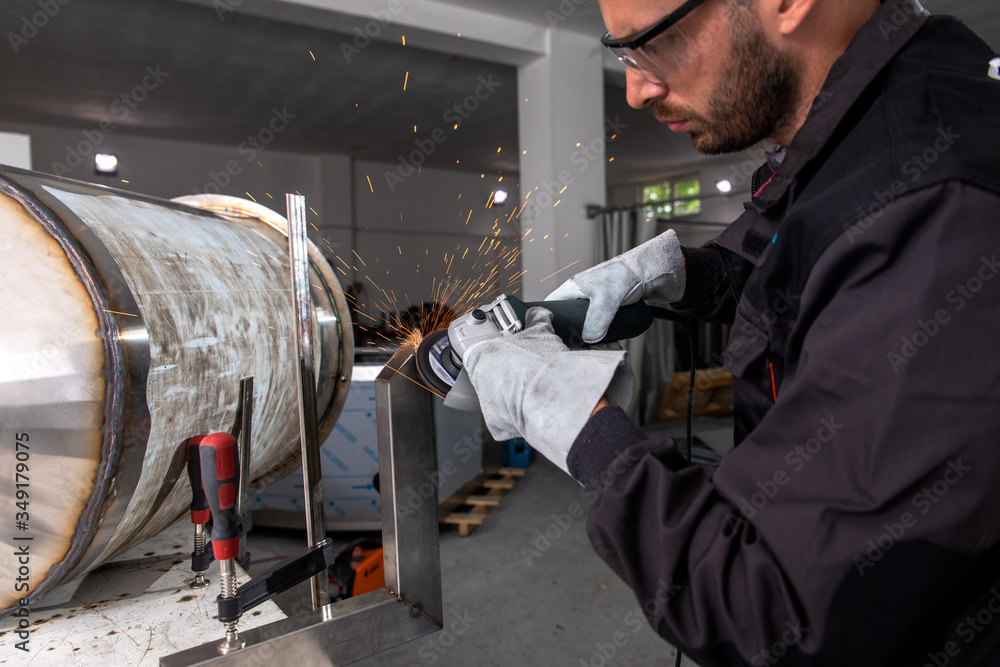 Industrial worker with angle grinder working on metal structure at workshop. Industrial worker with angle grinder working on metal structure at workshop.