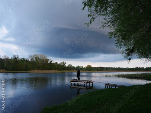 Stormy sky over the river. Man fishing under the storm. Local tourism