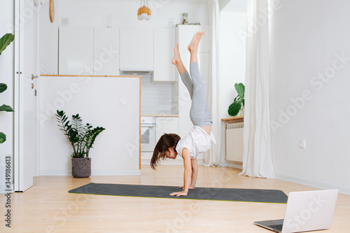 Girl staying in shape, walking on hands at home during isolation