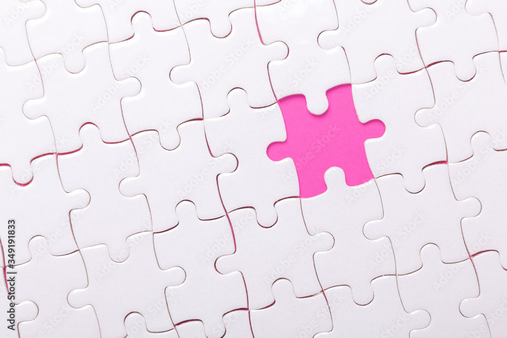 White jigsaw puzzle with with one piece missing and pink background White jigsaw puzzle with with one piece missing and pink background