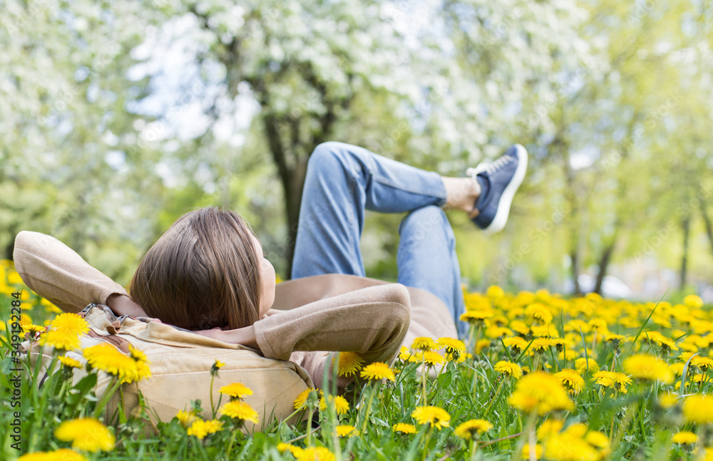 Relaxing woman lying on spring blooming meadow. Girl resting in summer park. Enjoy life, having fun, leisure, relaxation, lifestyle concept Relaxing woman lying on spring blooming meadow. Girl resting in summer park. Enjoy life, having fun, leisure, relaxation, lifestyle concept