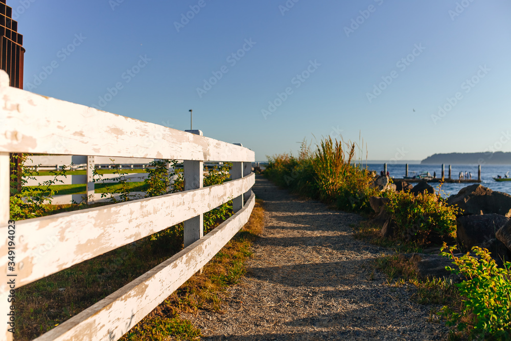 Sandy path to the sea along a white wooden fence