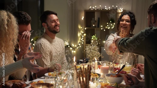 holidays, celebration and people concept - happy smiling friends having christmas dinner and sharing food at home in evening