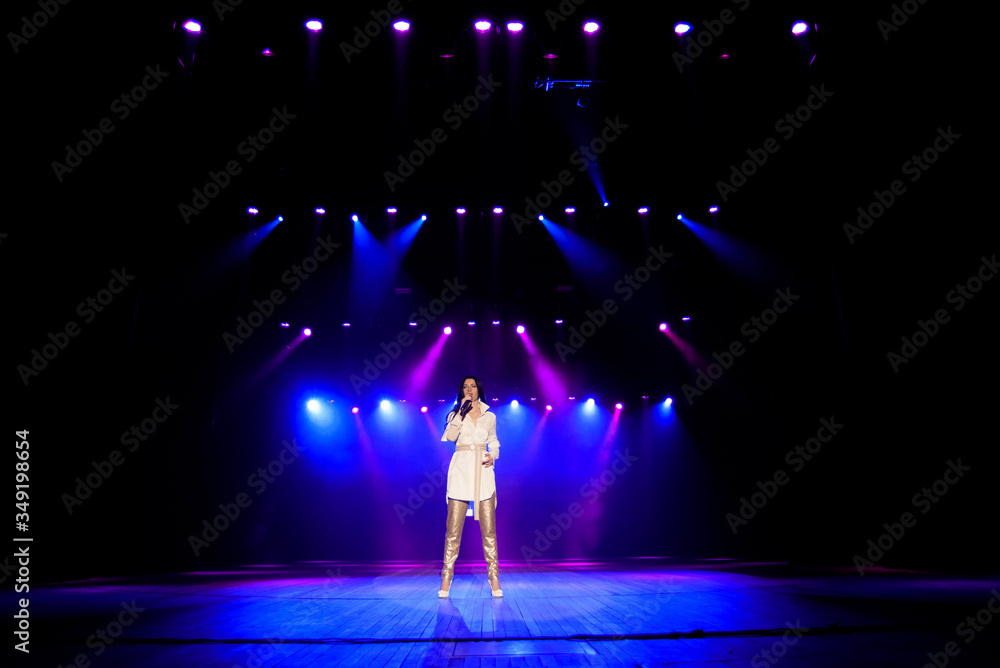 Singer star performing solo set on scene in music hall. Neon background, smoke, concert spotlights.