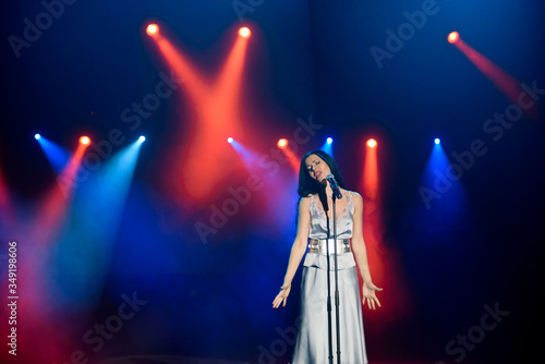 Singer with microphone on the colorful light stage background