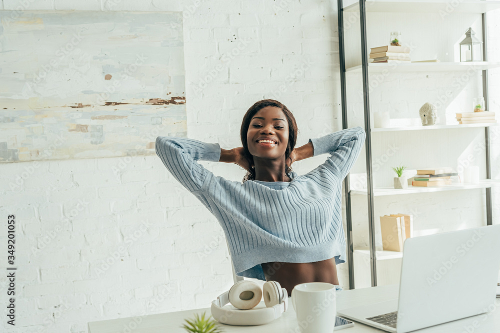 © LIGHTFIELD STUDIOS - cheerful african american freelancer stretching while sitting near laptop, wireless headphones and coffee cup © LIGHTFIELD STUDIOS - cheerful african american freelancer stretching while sitting near laptop, wireless headphones and coffee cup