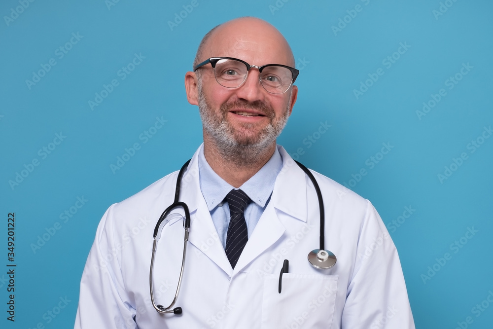 Smiling mature doctor in white coat and stethoscope isolated on blue background Smiling mature doctor in white coat and stethoscope isolated on blue background