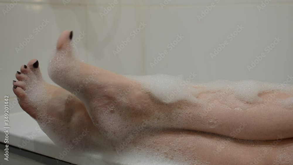 Feet of a young girl who bathes in a bathtub with foam Feet of a young girl who bathes in a bathtub with foam