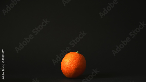 Fresh single orange on a black background