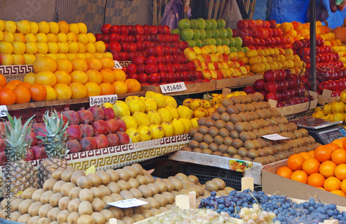 A fruit vendor's booth in Armenia filled with colorful fruit. Signs show the names of the respective fruits.