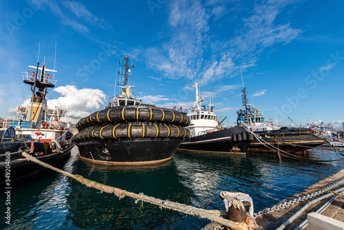 Four tugboats moored in the port of La Spezia, tied with hawsers to the quay. Liguria, Italy, Europe