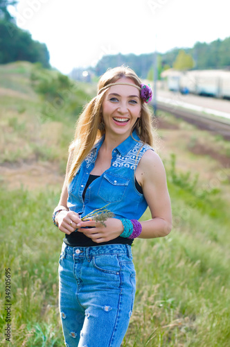 vertical portrait of a cheerful slender blonde on a background of nature and railway tracks