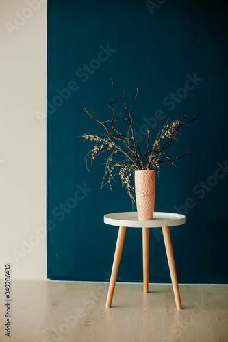 vase with dry grass on the table on a blue background