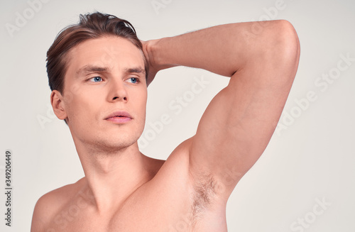 Brutal young Caucasian shirtless man shows muscles.