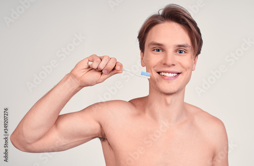 Charming shirtless young guy with a toothbrush.
