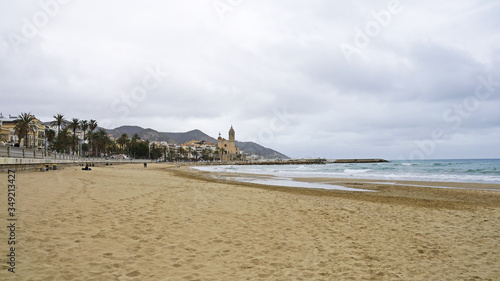 A beautiful beach in Sitges, near Barcelona. Light waves roll onto Spain's Mediterranean beach. Beautiful architecture of Catalonia. Unique landscapes of the Iberian Peninsula