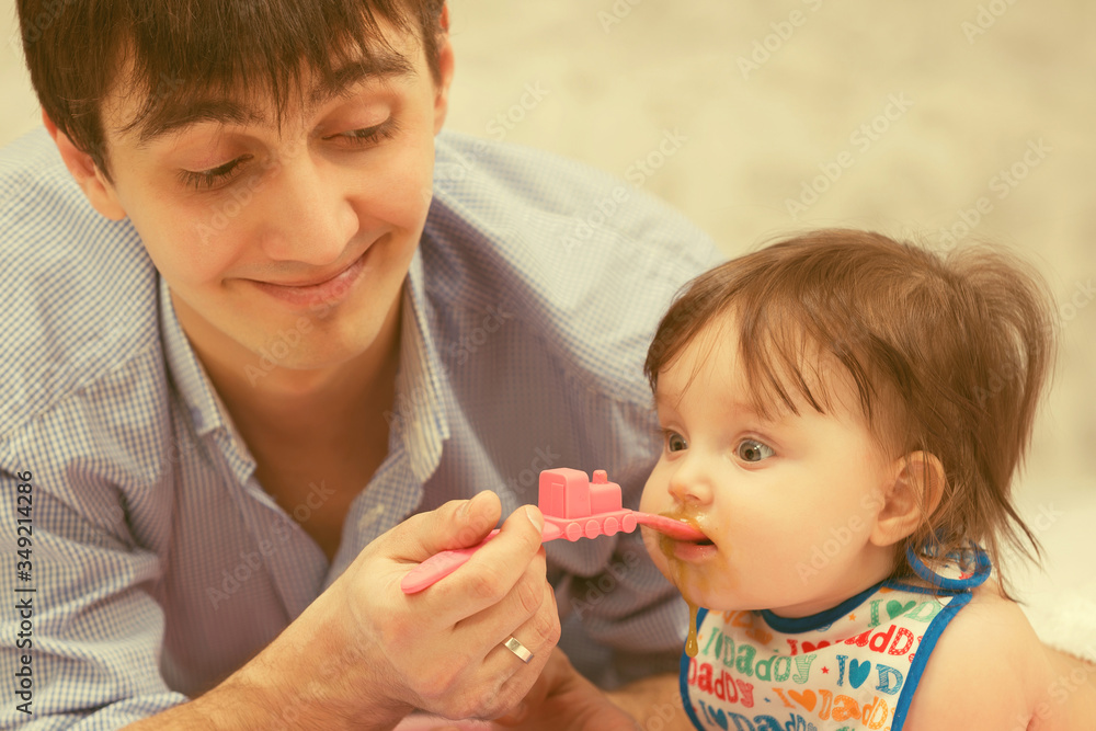 Happy young father feeding baby girl Happy young father feeding baby girl