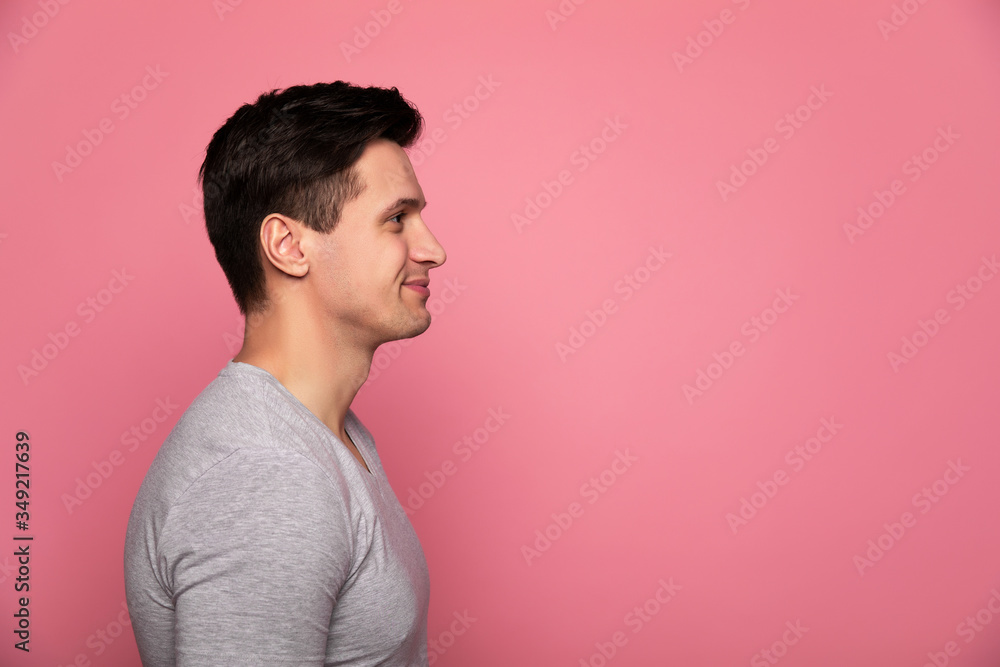Handsome man. Close-up photo of an attractive man in a grey t-shirt, who is standing in profile and smiling. Handsome man. Close-up photo of an attractive man in a grey t-shirt, who is standing in profile and smiling.