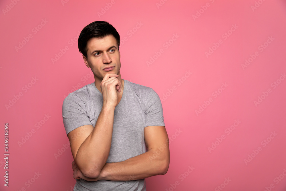 Overthinking. Close-up photo of a young athletically built man, who is looking aside and holding his chin, while standing with folded hands. Overthinking. Close-up photo of a young athletically built man, who is looking aside and holding his chin, while standing with folded hands.