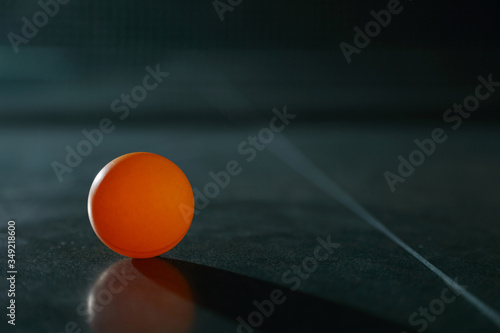 Orange ping pong ball on a green table